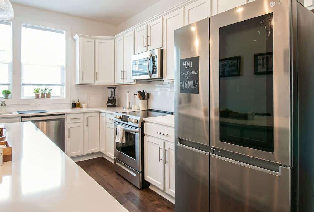 A modern kitchen with white cabinets, stainless steel appliances, and a large island.