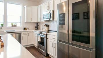 A modern kitchen with white cabinets, stainless steel appliances, and a large island.