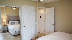 Une chambre d’hôtel avec un lit, une table de chevet, une lampe et un ventilateur de plafond.