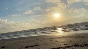 Ein Strand mit untergehendem Sonnenuntergang über dem Meer, der eine ruhige und friedliche Atmosphäre schafft.