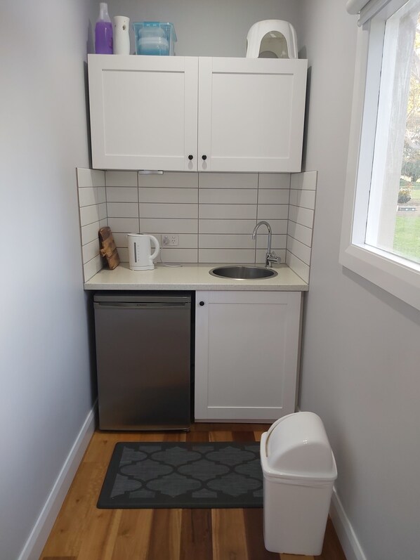 A compact kitchen with white cabinets, a stainless steel sink, and a dishwasher. - Farm stay Guesthouse (Gnarwarre)