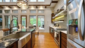 Una cocina amplia con una isla grande, electrodomésticos de acero inoxidable y vistas al exterior.