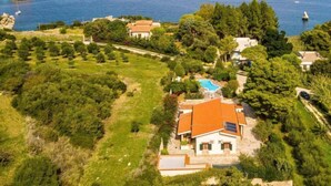 Una propiedad costera con piscina, varias casas y exuberante vegetación.