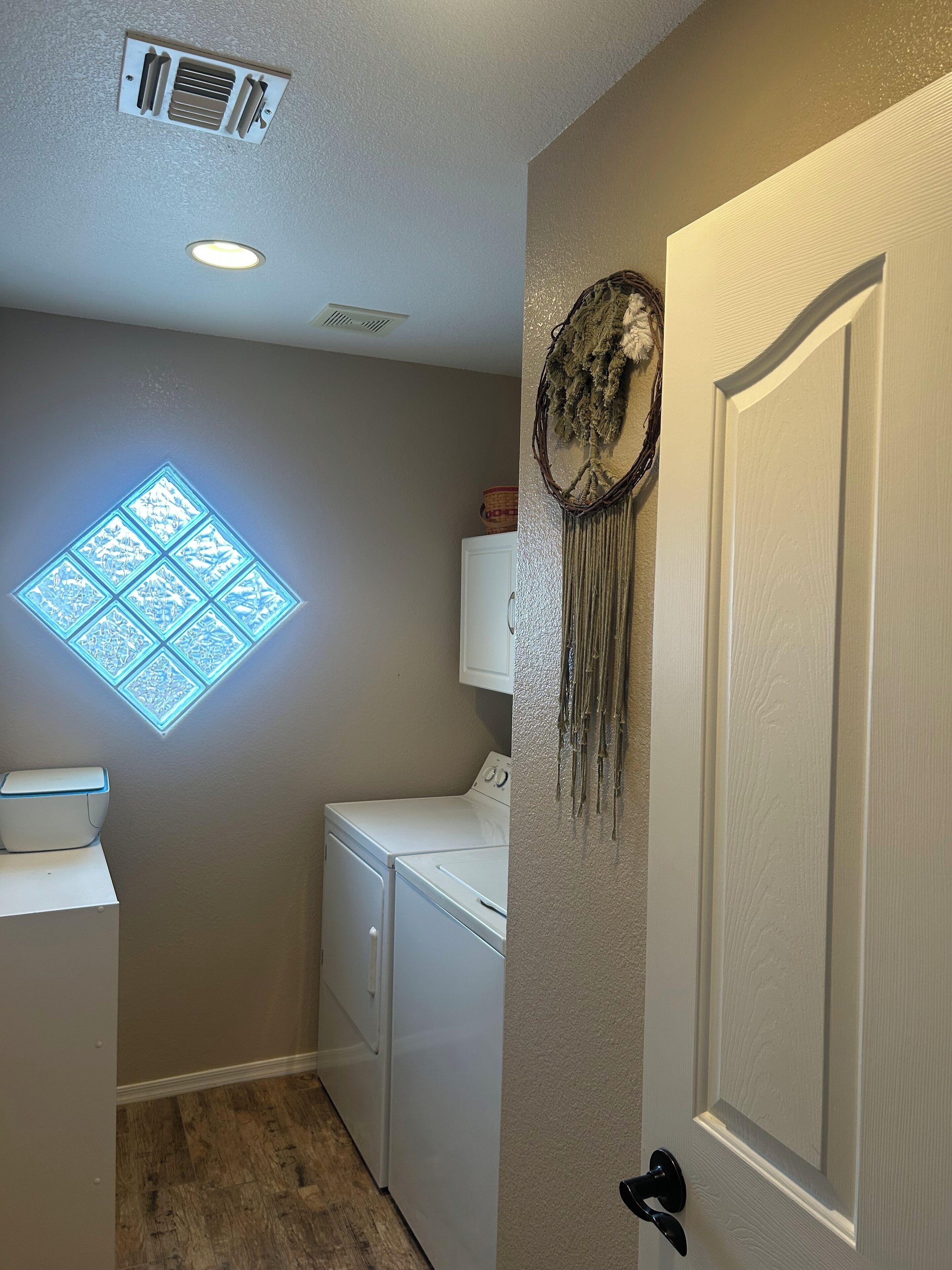 A laundry room with a white washing machine, a dryer, and a wall-mounted vent.