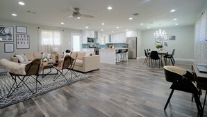 A spacious living area with a sofa set, a coffee table, and a dining table with chairs.