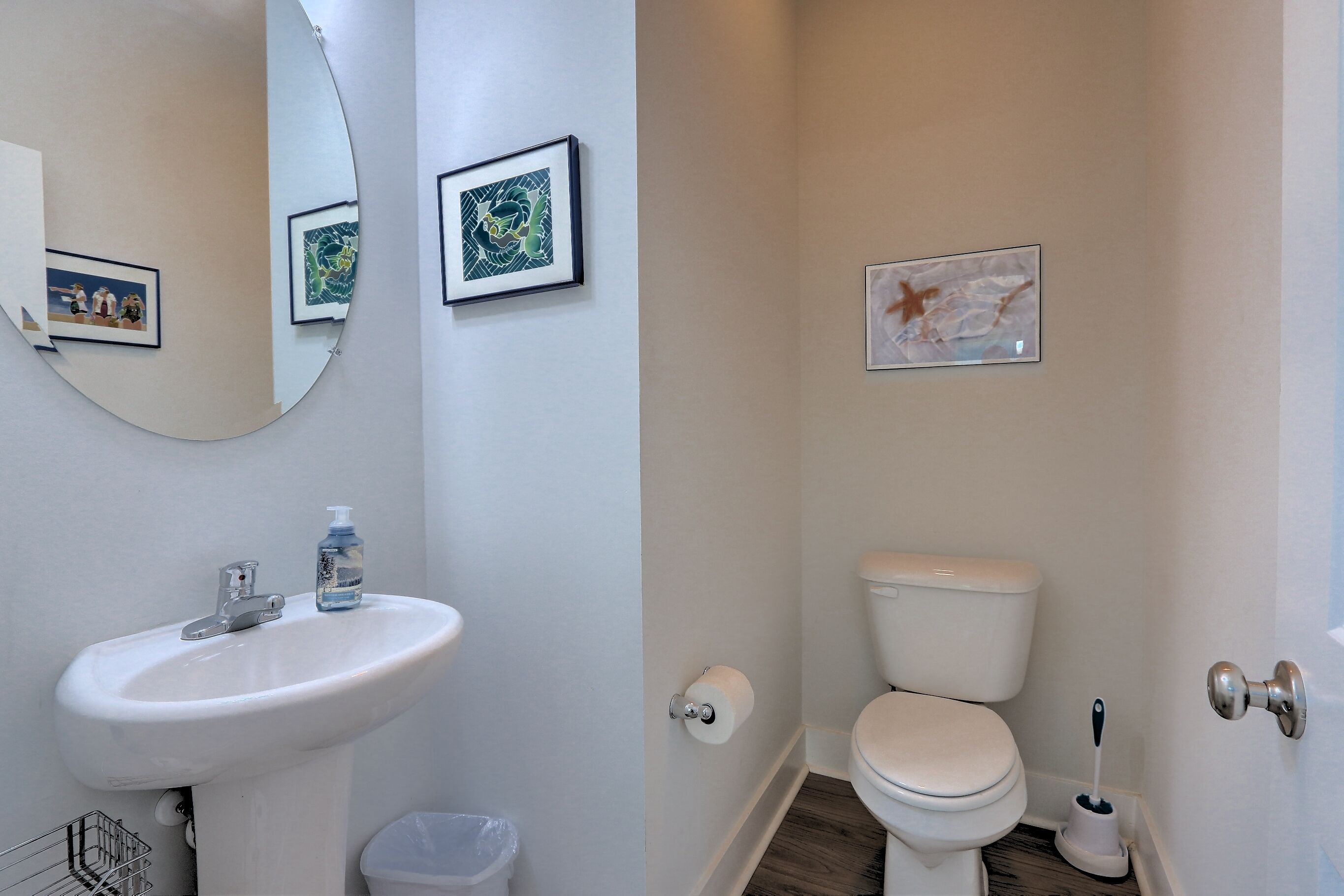 Un baño con lavamanos, inodoro y espejo blancos.