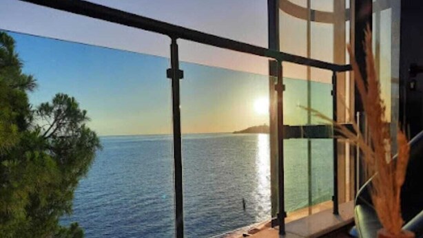 Un balcon avec vue sur la mer et sur le coucher du soleil.