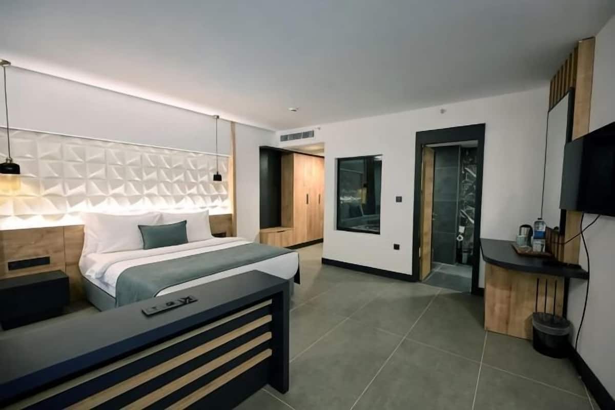 Ein modernes Hotelzimmer mit Bett, Nachttisch, Fernseher und Schreibtisch.