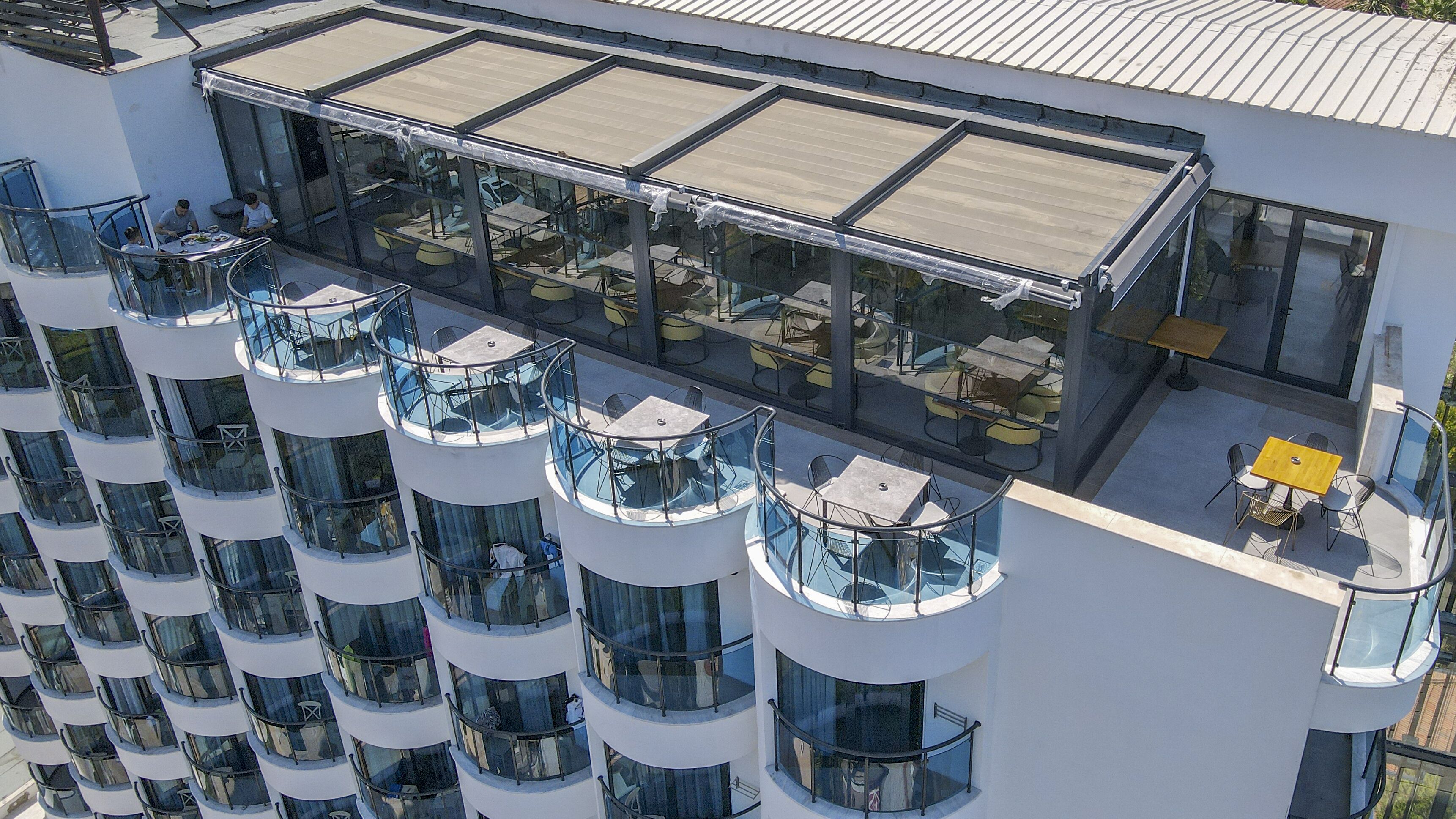 Un hotel moderno con varios balcones, zonas de estar al aire libre y fachada de vidrio.