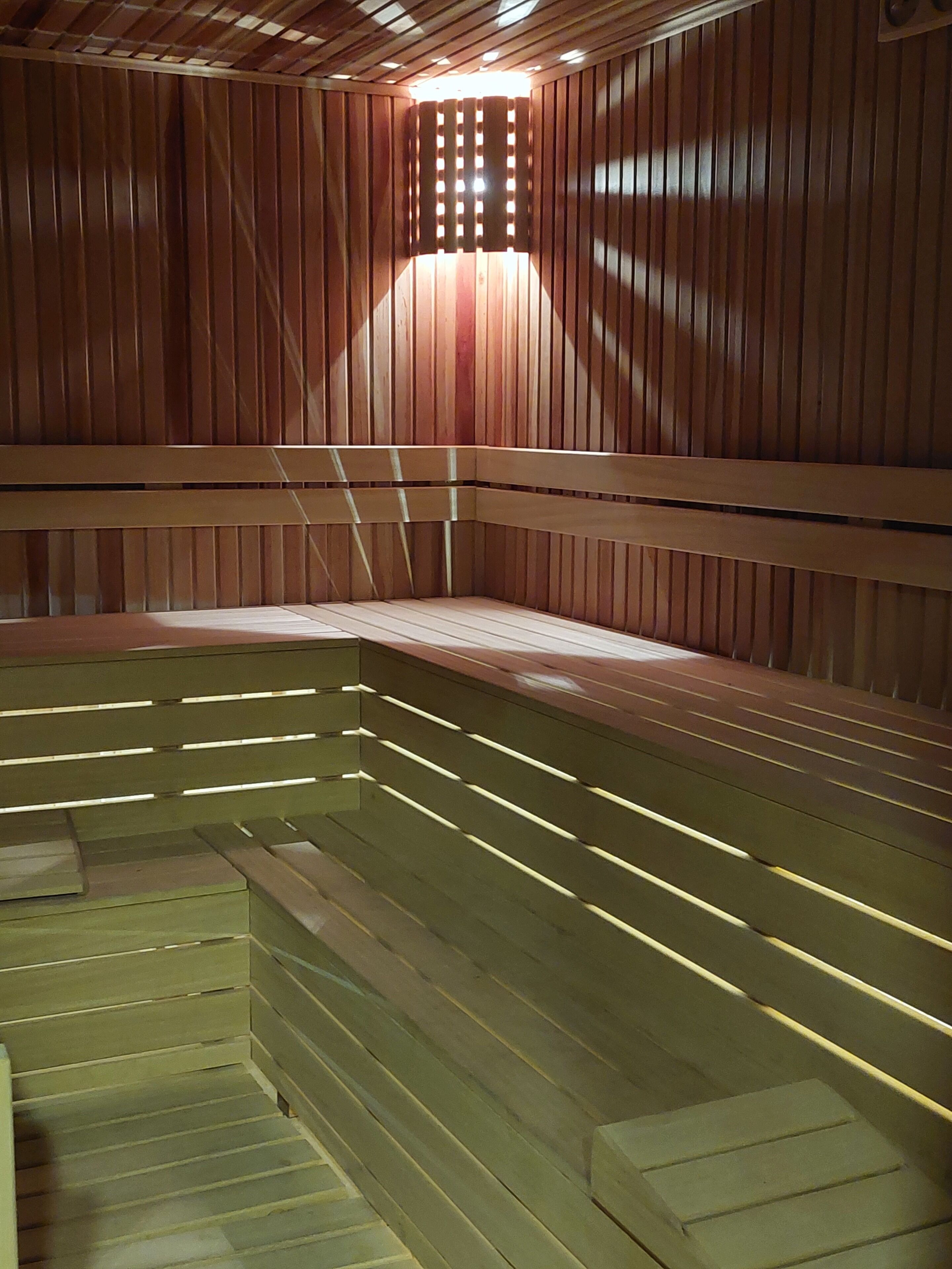 A sauna with wooden benches and a sloped floor design.