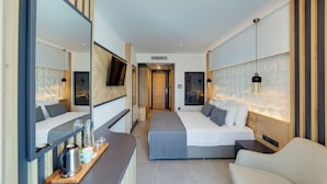 Une chambre d’hôtel moderne équipée d’un grand lit, d’un canapé, d’un bureau avec une bouilloire et d’un miroir.