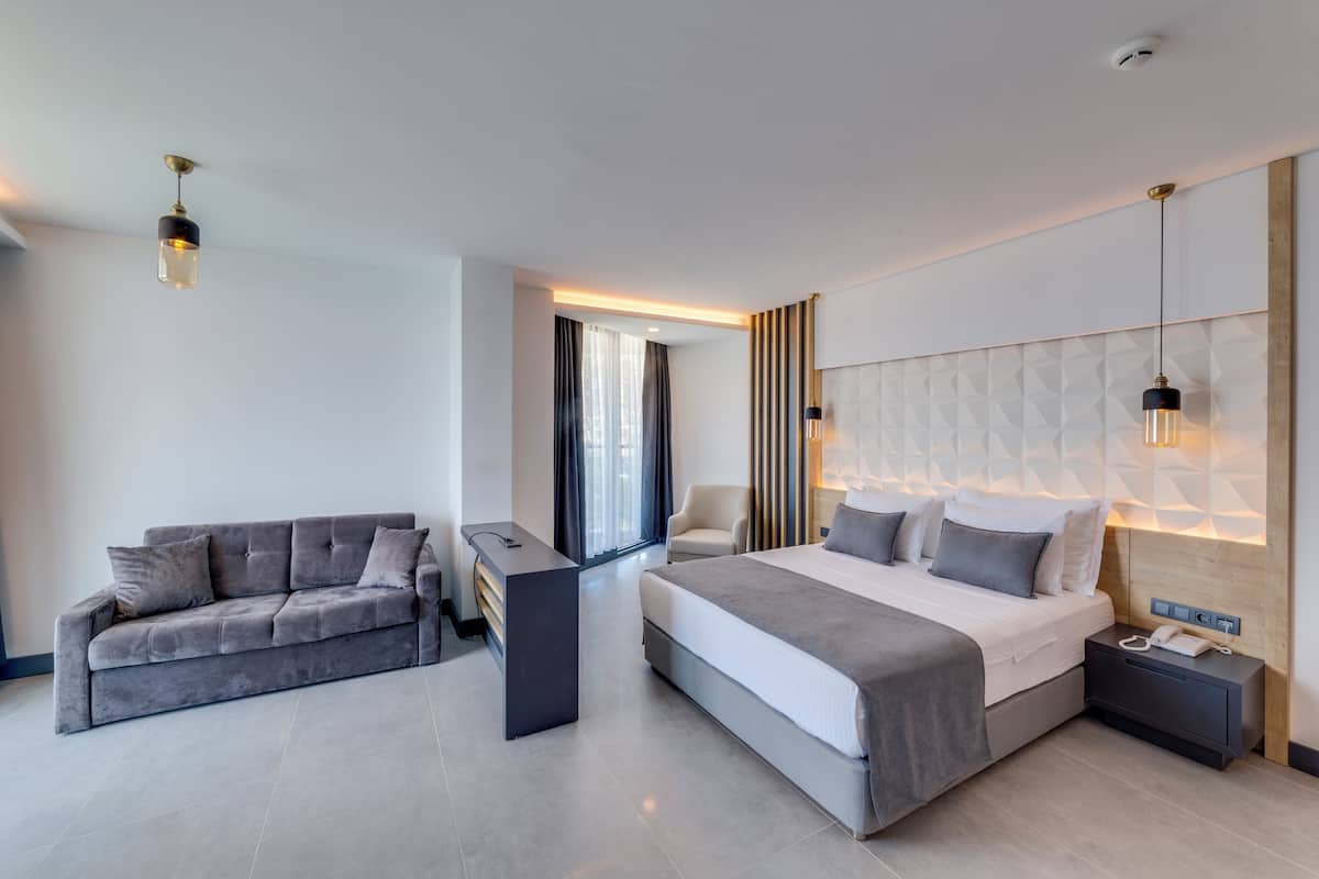 Ein modernes Hotelzimmer mit einem großen Bett, einer Couch, einem Schreibtisch und einem Nachttisch mit Telefon.
