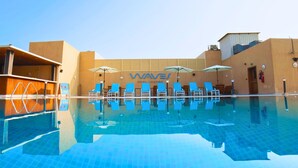 A swimming pool with blue tiles, lounge chairs, and umbrellas. -  Asma Hotel (Dubai)