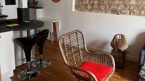 Una cucina moderna con rivestimento in pietra a parete, una zona pranzo con tavolo e sedie rotonde e una sedia in vimini con cuscino rosso.