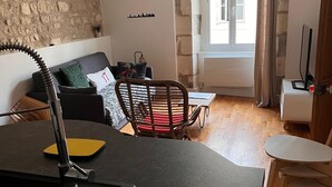 Un accogliente soggiorno con parete in pietra, angolo ristoro con tavolo e sedie, e vista all'esterno da una finestra.