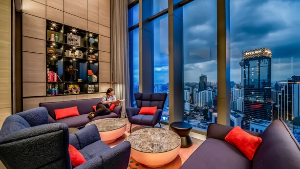 Un’elegante area relax con sedute confortevoli, un’ampia finestra con vista sulla città e una libreria ben ordinata.