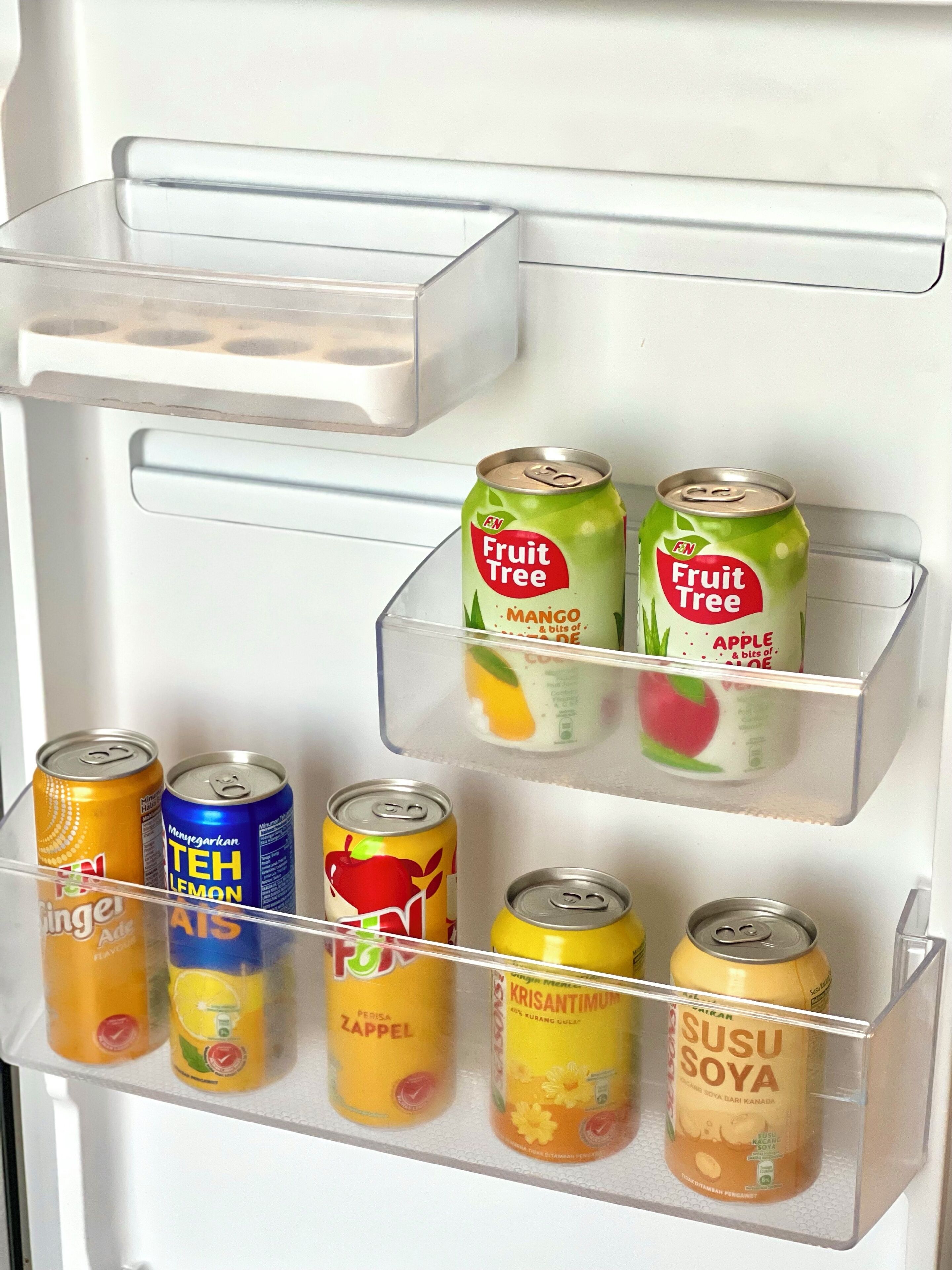 Un réfrigérateur doté de plusieurs  étagères contenant diverses canettes de boissons.