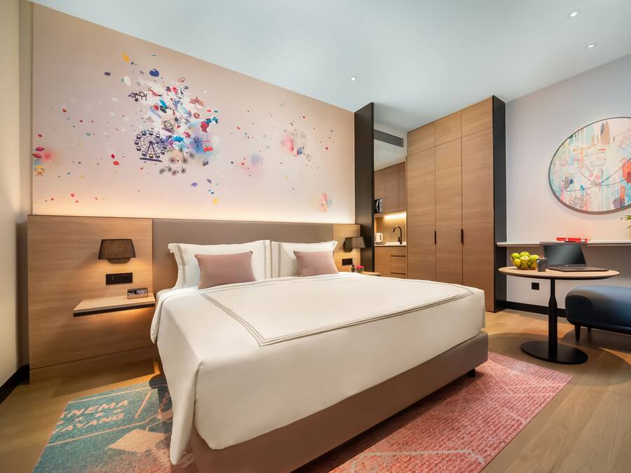 Une chambre d’hôtel moderne dotée d’un grand lit, d’un bureau et d’un coin salon.