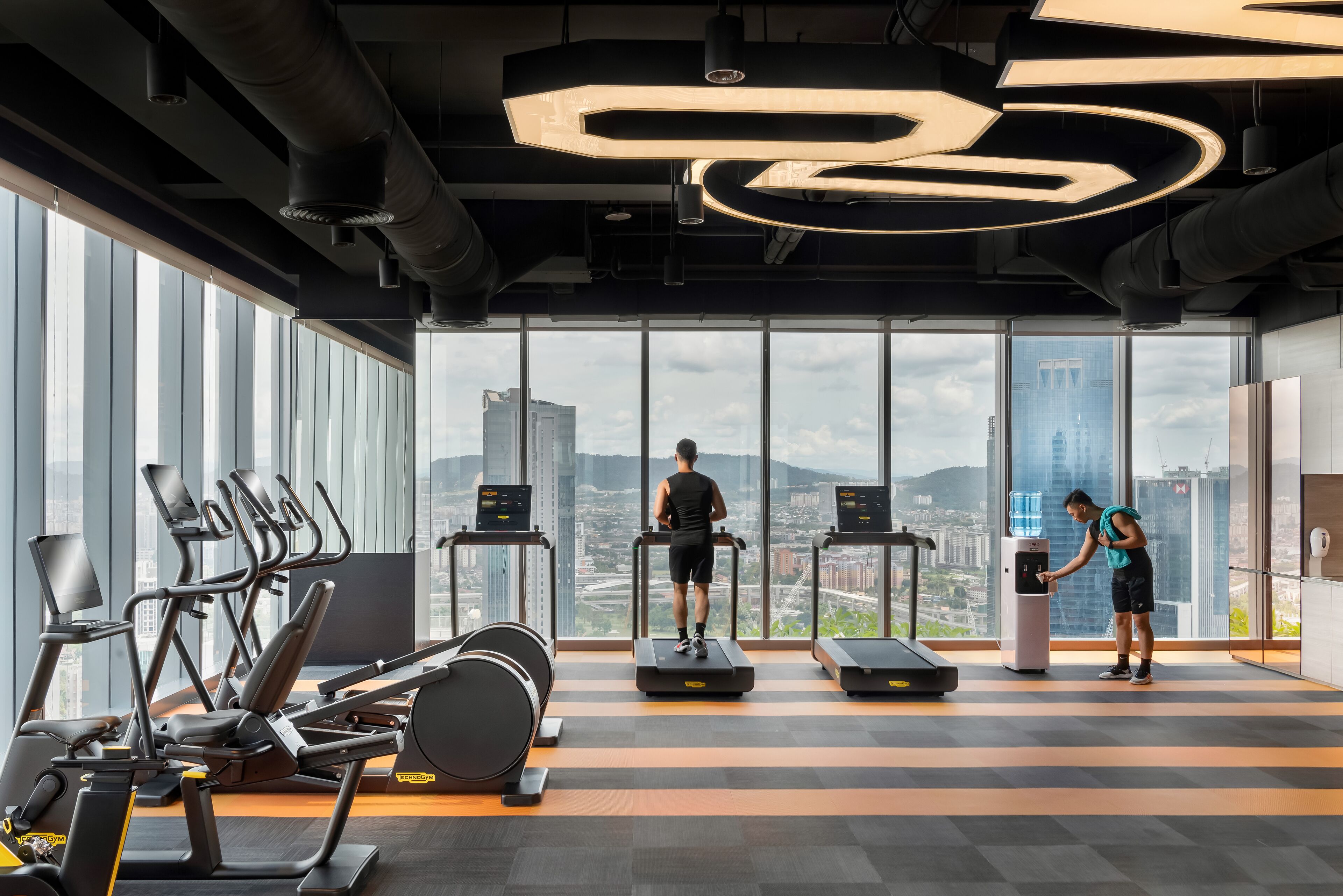 A gym with treadmills, elliptical machines, and a water dispenser.