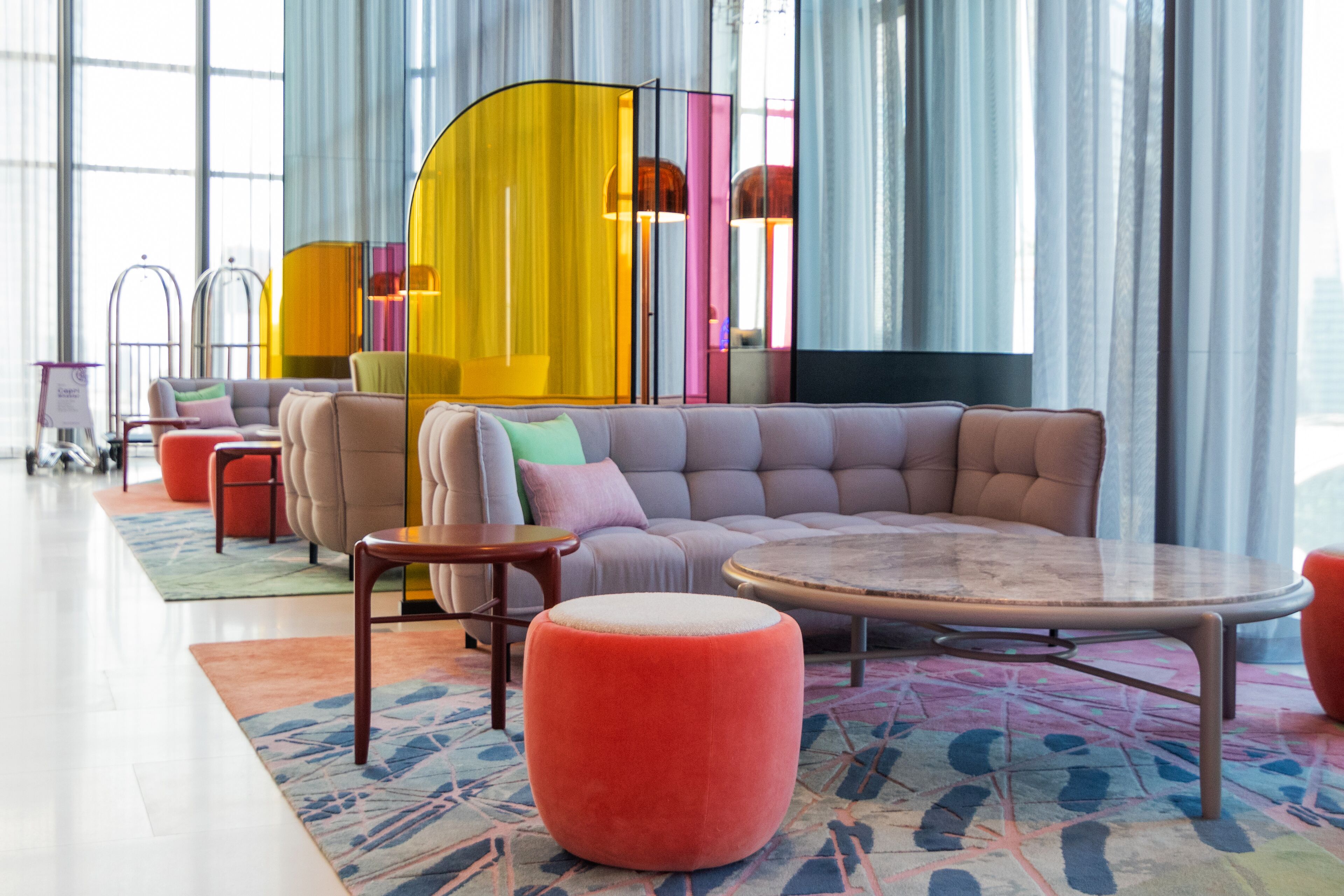A modern living room with a sectional sofa, ottomans, a coffee table, and a colorful rug.
