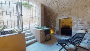 A stone-walled interior with a bed, a bench, and a small table with plants. - Grignan Provencal Tower – Stunning Views & Elegant Stay (Grignan)