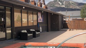 A pool area with a wooden deck, outdoor seating, and a mountain view in the background.
