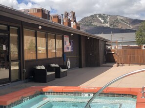 Un espace piscine doté d’une terrasse en bois, de sièges extérieurs et offrant une vue sur les montagnes en arrière-plan.