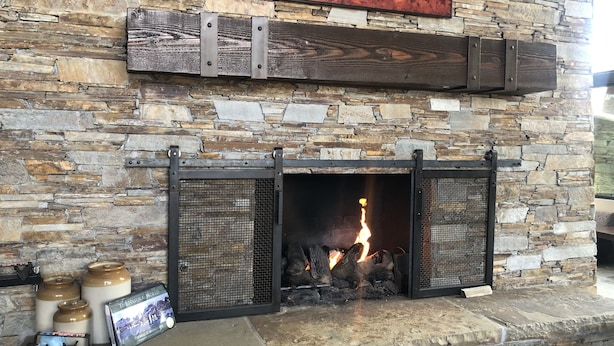 A stone fireplace with a metal screen, a framed picture above it, and decorative jars on the mantel.