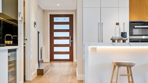 Una cocina moderna con una isla central, electrodomésticos de acero inoxidable y una puerta de madera con paneles de vidrio esmerilado.