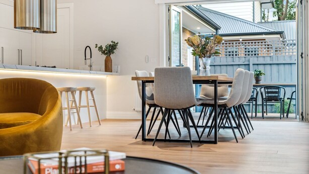 Una cocina moderna con barra, sillas de comedor y un sillón amarillo.