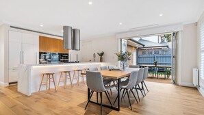 Una cocina moderna con armarios blancos, electrodomésticos de acero inoxidable y una isla central con taburetes de bar.