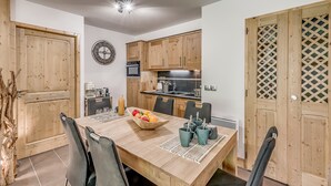 Una cocina moderna con armarios de madera, un microondas y un lavamanos. Hay una mesa de comedor con sillas y un frutero.