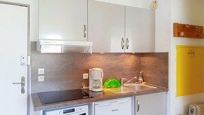 Een compacte keuken met een Bosch koffiezetapparaat, een Beko oven, een spoelbak en een geel kastje.