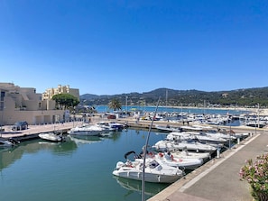 A marina with boats docked, a clear sky, and a hilly landscape in the background.