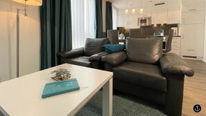Ein modernes Wohnzimmer mit einer Couch, einem Tisch und einer Küche im Hintergrund.