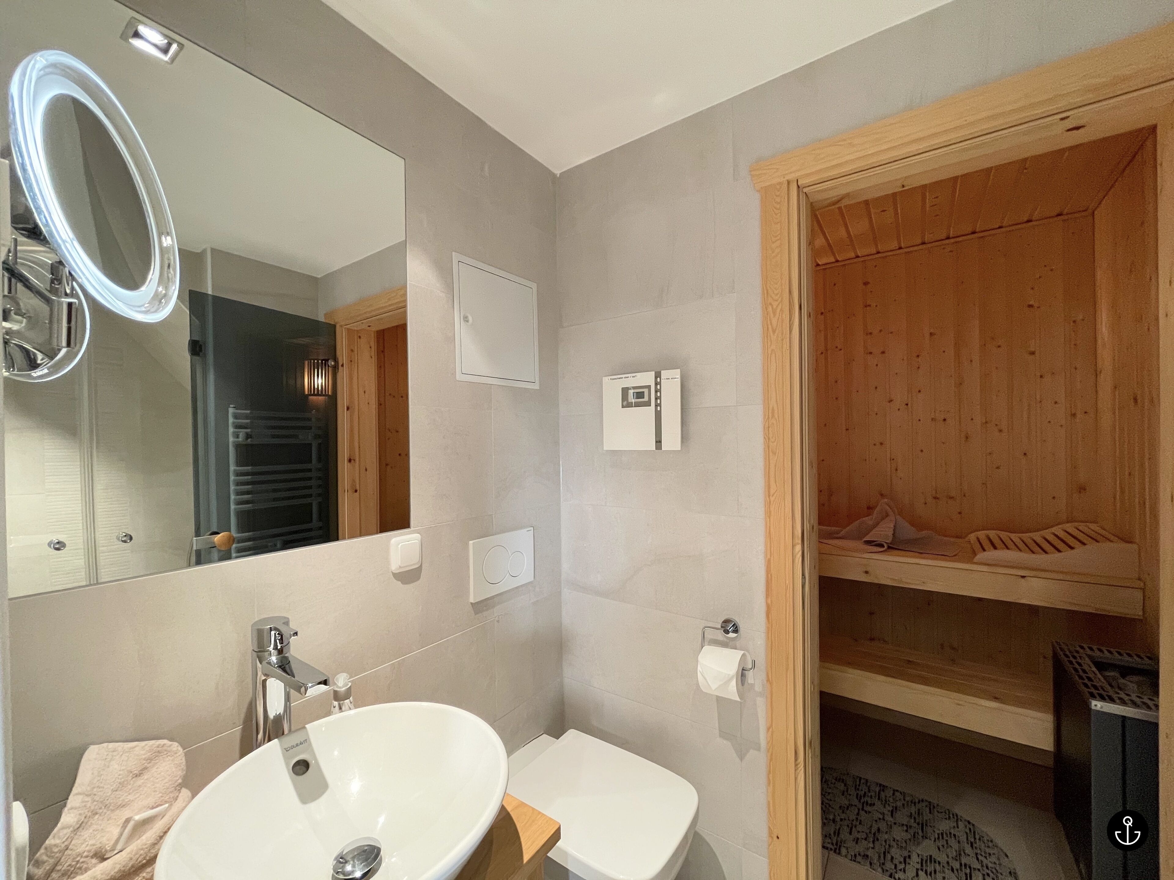 A bathroom with a sink, mirror, and wooden sauna.