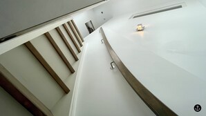 Ein modernes Interieur mit weißer Arbeitsplatte, Holzlamellenstruktur und einem kleinen beleuchteten Objekt auf der rechten Seite.