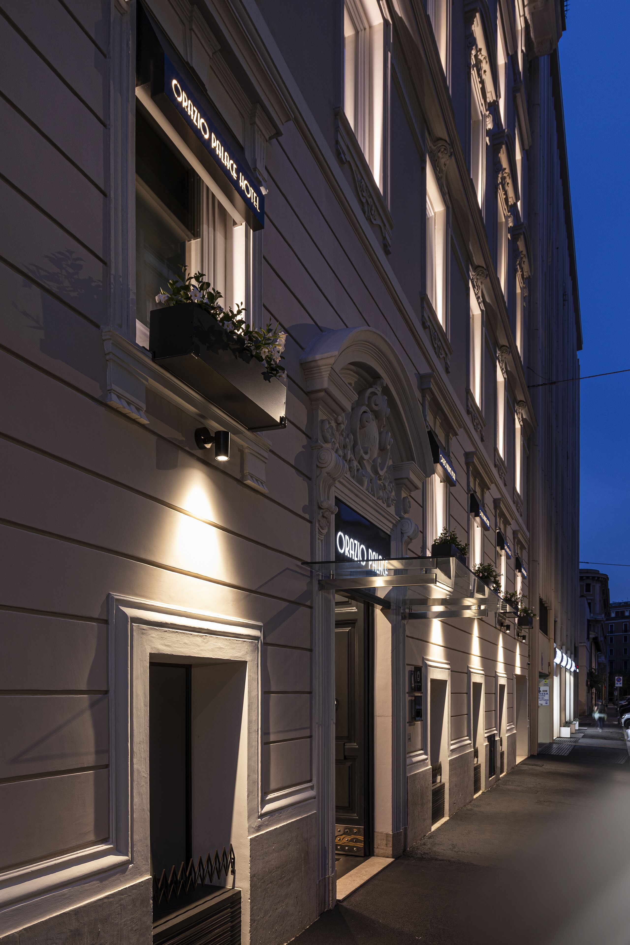 A hotel facade with ornate architectural details, including a balcony with potted plants and a sign reading "Orio Palace Hotel."