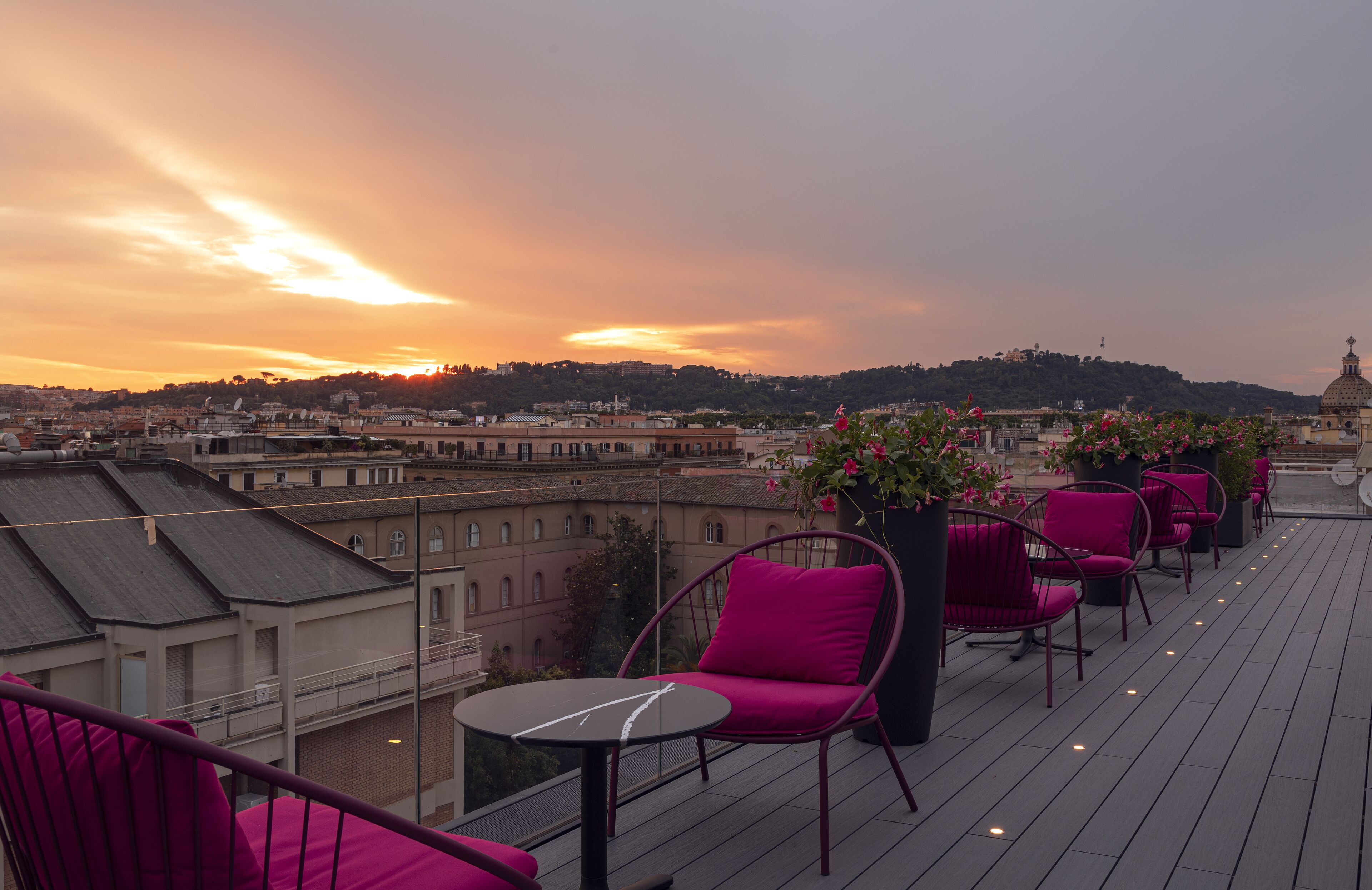 A rooftop terrace with seating and a view of the cityscape at sunset.
