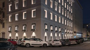 Un hotel de varios pisos con ventanas iluminadas y un estacionamiento.