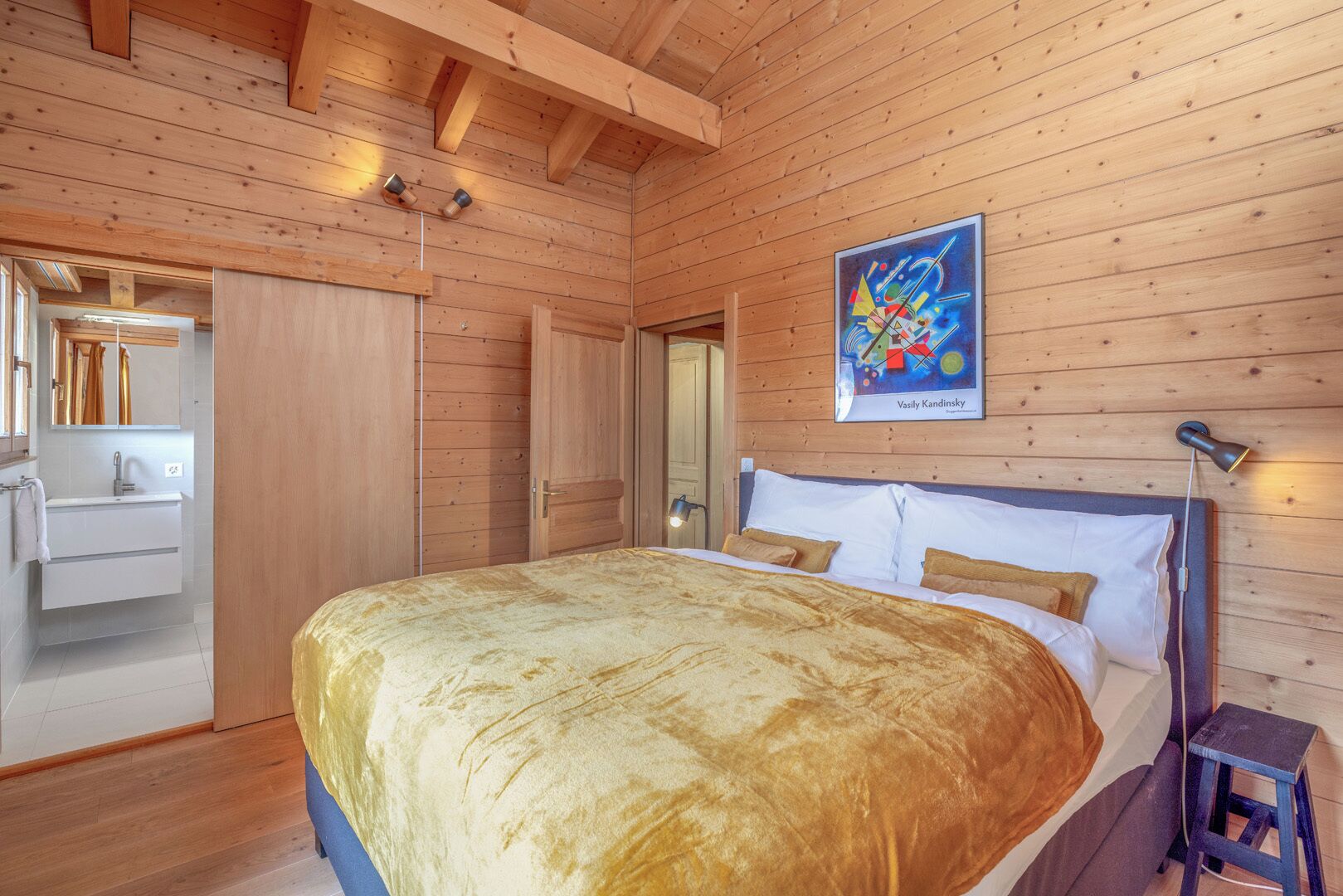 Ein Schlafzimmer mit Holzwänden, einem Bett, einem Nachttisch, einem Gemälde und einem Kleiderschrank.