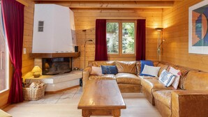A cozy cabin interior with a wooden interior, a fireplace, a sofa, and a dining table. - Chalet Mouettes (Riddes)