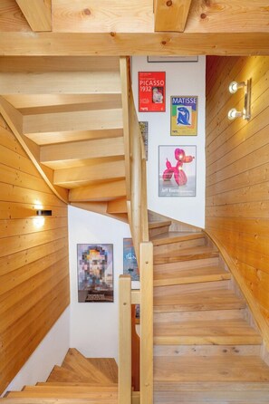 A wooden staircase with a handrail, wooden walls, and art posters including works by Picasso and Matisse. - Chalet Mouettes (Riddes)