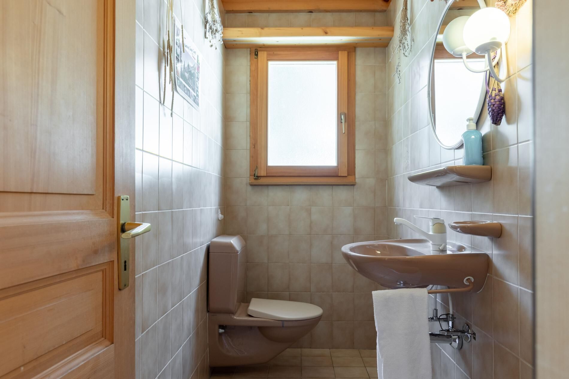 A compact bathroom with a toilet, sink, and window.