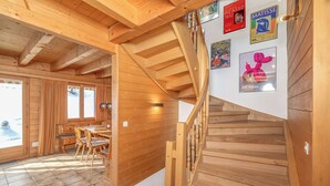 A wooden interior with a spiral staircase, wooden walls, and a dining area with a view of the outside. - Chalet Mouettes (Riddes)