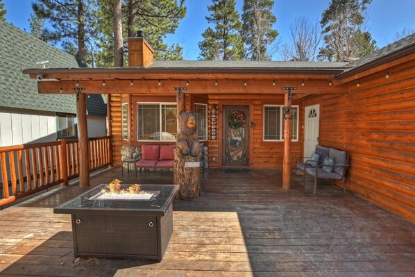 A wooden cabin with a deck, a fireplace, and a bench.