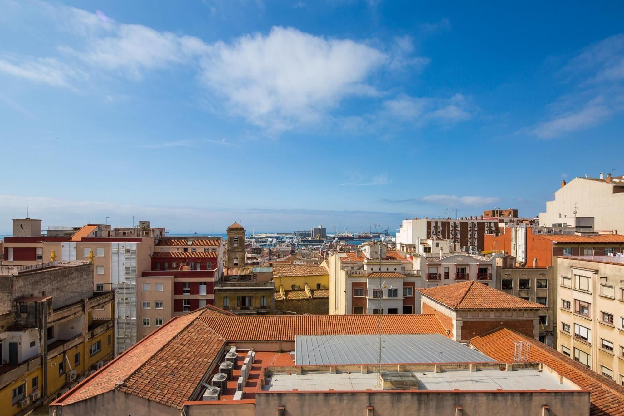 Un paysage urbain mêlant des immeubles résidentiels et commerciaux, une tour imposante et un ciel bleu dégagé.