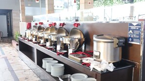 A buffet setup with multiple food dispensers, a large rice cooker, and a sign indicating COVID-19 safety measures. - Grand Victoria Hotel (Samarinda)