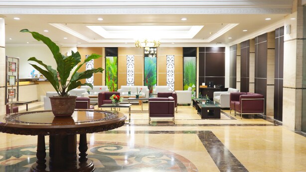 A spacious lobby with a central seating area, a large potted plant, and a decorative fountain. - Grand Victoria Hotel (Samarinda)