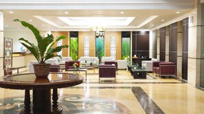 A spacious lobby with a central seating area, a large potted plant, and a decorative fountain. - Grand Victoria Hotel (Samarinda)